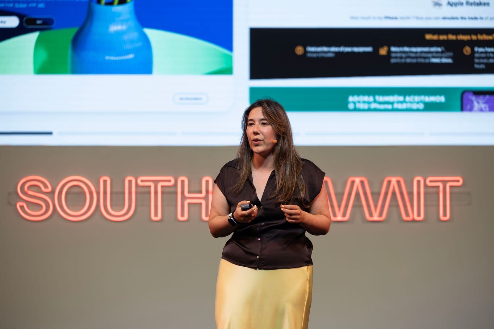 A LoopOS team member on stage at South Summit Madrid, with the South Summit sign and event screen behind.